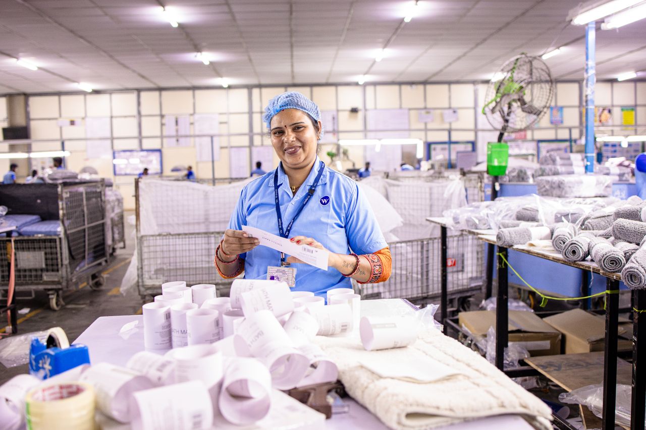 Female textile worker inspecting labels in a factory setting, showcasing blue-collar work environment.