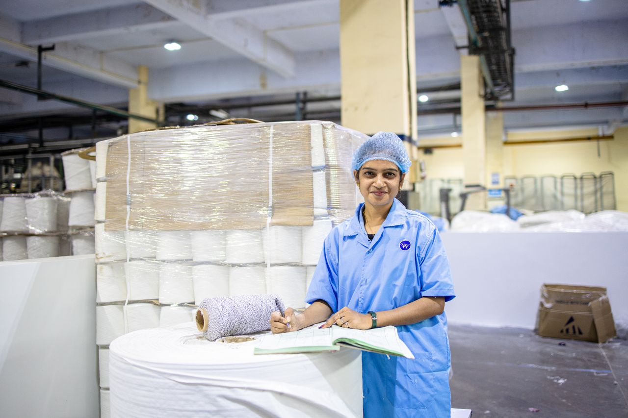 Female worker in textile factory checking yarn rolls, showcasing industry precision.